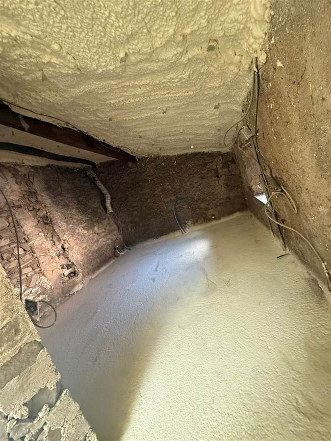 Sous-face de plancher isolée par mousse polyuréthane dans un vide sanitaire en pierre